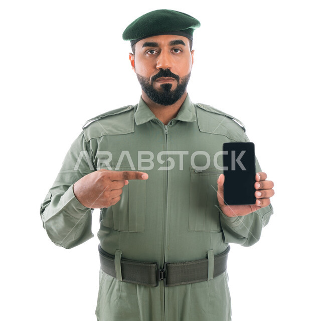 برامج وانظمة حماية الهاتف المحمول، بورتريه لرجل أمن عربي خليجي إماراتي يرتدي بدلة الأمن الخضراء ويشير بإصبع السبابة نحو الجوال بشاشة سوداء فارغة، إستخدام تطبيقات الأمن والسلامة في الهاتف الذكي، خلفية بيضاء