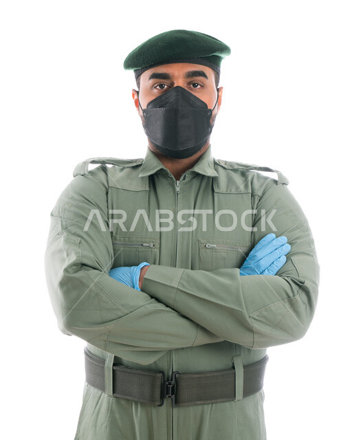 الوقوف بإستقامة وإنضباط، بورتريه لمحقق أدلة جنائية عربي خليجي إماراتي يرتدي الكمامة الواقية والقفازات وبدلة الأمن الخضراء بأيدي متقاطعة، إيماءات يدين تدل على الثقة، جمع الأدلة للتحقق والتحري في موقع الجريمة، البحث لكشف حقائق الجرائم، خلفية بيضاء