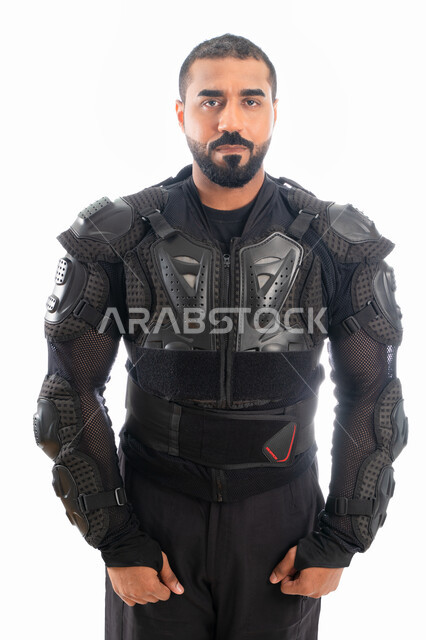 الوقوف بإستقامة وإستعداد وإنضباط، بورتريه لشرطي عربي خليجي إماراتي من قوات التدخل السريع (سوات) يرتدي البدلة العسكرية السوداء، الحفاظ على الأمن والأمان، إيماءات وجه ويدين تدل على الثقة، خلفية بيضاء