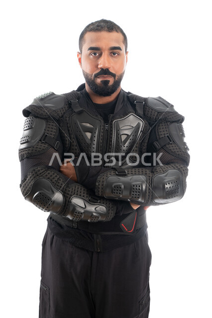 الحفاظ على الأمن والأمان، الوقوف بإستقامة وإنضباط، بورتريه لشرطي عربي خليجي إماراتي من قوات التدخل السريع (سوات) يرتدي البدلة العسكرية السوداء بأيدي متقاطعة، إيماءات وجه ويدين تدل على الثقة، خلفية بيضاء