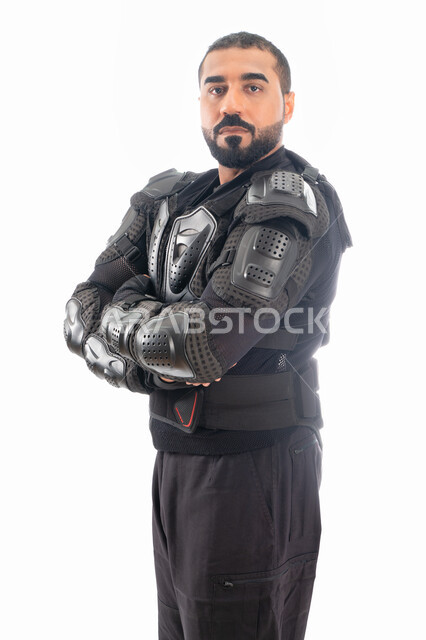 إيماءات وجه ويدين تدل على الثقة، بورتريه لشرطي عربي خليجي إماراتي من قوات التدخل السريع (سوات) يرتدي البدلة العسكرية السوداء بأيدي متقاطعة، الحفاظ على الأمن والأمان، الوقوف بإستقامة وإنضباط، خلفية بيضاء