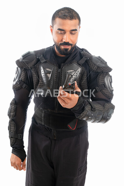 الحفاظ على الأمن والأمان، الوقوف باستقامة واستعداد وانضباط، بورتريه لشرطي عربي خليجي إماراتي من قوات التدخل السريع (سوات) يرتدي البدلة العسكرية السوداء ويستخدم جهاز الارسال والاستقبال اللاسلكي، خلفية بيضاء