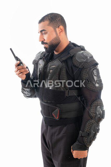 قوات التدخل السريع (سوات)، الوقوف باستقامة واستعداد وانضباط، بورتريه لشرطي عربي خليجي إماراتي يرتدي البدلة العسكرية السوداء ويستخدم جهاز الارسال والاستقبال اللاسلكي، الحفاظ على الأمن والأمان، خلفية بيضاء