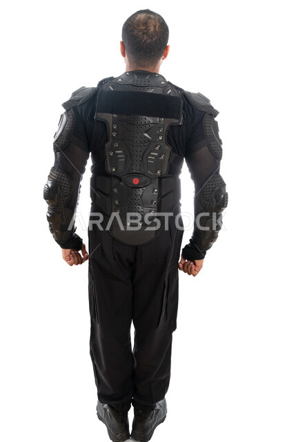 الحفاظ على الأمن والأمان، الوقوف باستعداد وانضباط، بورتريه من الخلف لشرطي عربي خليجي إماراتي يرتدي البدلة العسكرية السوداء، قوات التدخل السريع (سوات)، صورة الجسم بالطول الكامل، خلفية بيضاء