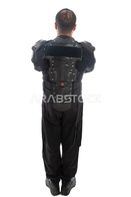 الوقوف باستعداد وانضباط، قوات التدخل السريع (سوات)، بورتريه الخلف لشرطي عربي خليجي إماراتي من يرتدي البدلة العسكرية السوداء، الحفاظ على الأمن والأمان، صورة الجسم بالطول الكامل، خلفية بيضاء