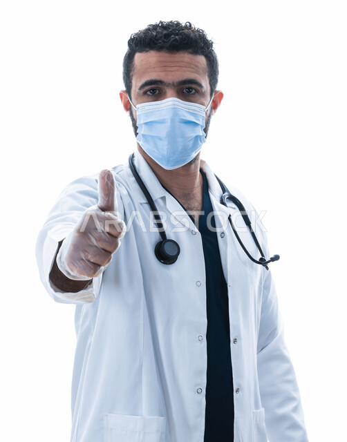 ايماءات يد تدل على علامه الجودة في القطاع الصحي, بورتريه مقرب لطبيب سعودي يرتدي الكمامة و المعطف الطبي وسماعه الطبيب لسماع نبضات القلب, شاب عربي اماراتي خليجي يوضح  مفهوم الطب والرعاية الصحية, مهن ووظائف طبيه، خلفيه بيضاء