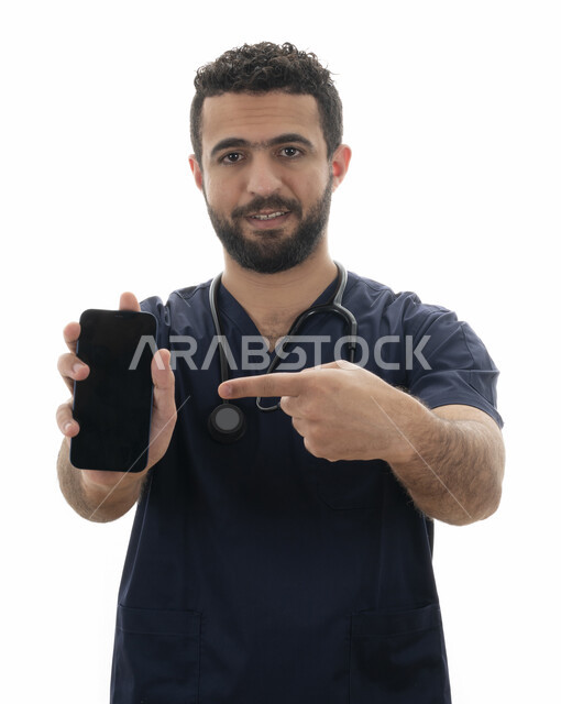 اتباع مفهوم الرعاية الصحية و الطب عبر برامج الهاتف المحمول, مهن ووظائف طبية في القطاع الصحي ،بورتريه مقرب لطبيب سعودي يقوم بتقديم الخدمات للمرضى بكل كفاءه, شاب عربي اماراتي خليجي يشير بإصبعه الى شاشه سوداء فارغه عبر الجوال
