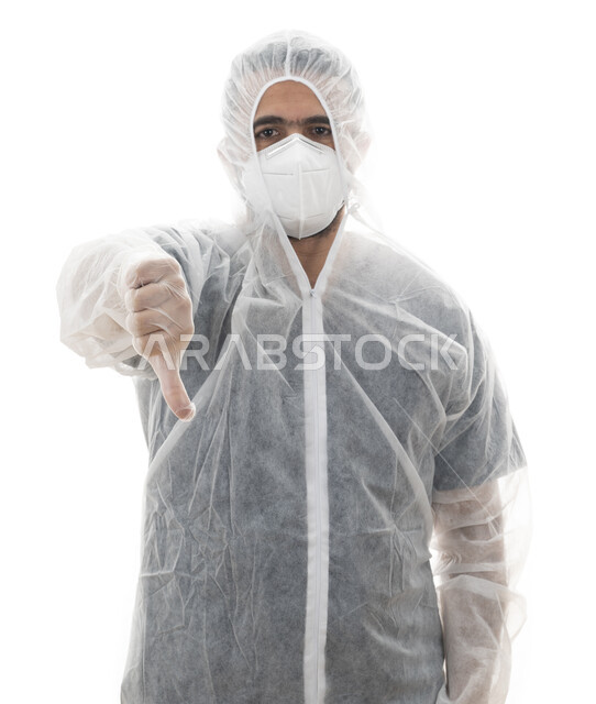 الالتزام بالاحترازات والإجراءات الوقائيه ضد كوفيد 19،بورتريه مقرب لطبيب سعودي يرتدي اللباس الابيض العازل الواقي لمكافحة فايروس كورونا , شاب عربي اماراتي خليجي يشير بإصبعه الابهام للاسفل , إتباع توصيات وزارة الصحة للحفاظ على السلامة