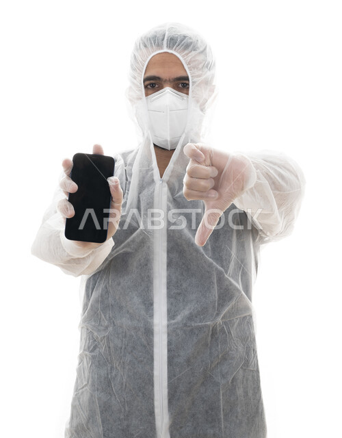 الالتزام بالاحترازات والإجراءات الوقائيه ضد كوفيد 19، بورتريه مقرب لطبيب سعودي يرتدي اللباس الابيض العازل الواقي لمكافحة فايروس كورونا , شاب عربي اماراتي خليجي يشير بإصبعه الابهام للاسفل لمنع استخدام الجوال, إتباع توصيات وزارة الصحة للحفاظ على السلامة