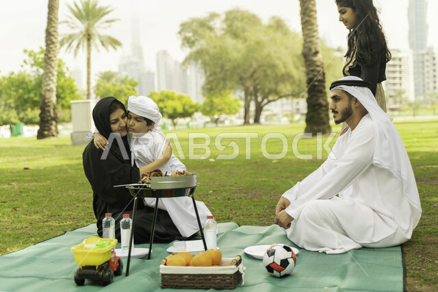 رحلة في أجواء صيفيه في الخارج, الاهتمام والاعتناء بالأطفال، مفهوم الامومة والتربية بالعطف و الحنان، أجواء عائلية مليئة بالحب، صورة مقربة لعائلة عربية اماراتية خليجية في إحدى المنتزهات, عائلة سعودية تقضي أوقات ممتعه في الحديقة، لمة عائلية سعيدة