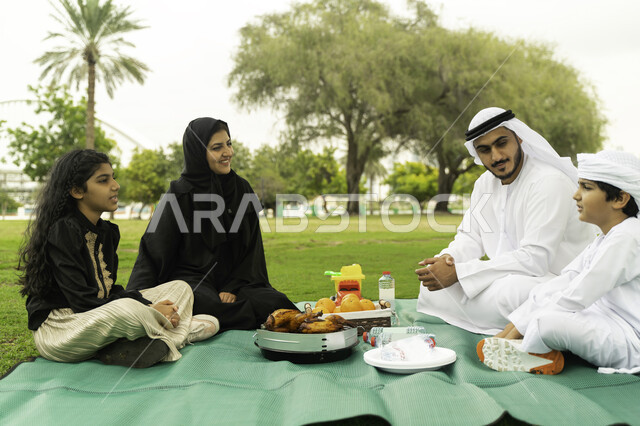 النقاشات والحوارات بين الافراد، تناول وجبة الغداء في أحد الحدائق, التنزه في الهواء الطلق, عائلة عربية اماراتية خليجية في إحدى المنتزهات في الخارج, عائلة سعودية تقضي أوقات ممتعه مع الابناء, الاعتناء بالأطفال والاهتمام بهم, انشطة ترفيهيه صيفية