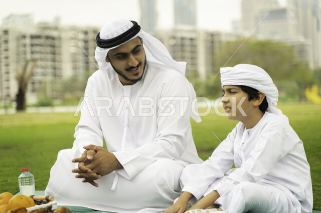 ايماءات تدل على السعادة، انشطة ترفيهيه صيفية، النقاشات والدردشة بين أفراد العائلة، التنزه في الهواء الطلق, والد عربي اماراتي خليجي في احدى المنتزهات مع ابنه في الخارج, عائلة سعودية تقضي أوقات ممتعه مع الابناء, الاعتناء بالأطفال والاهتمام بهم