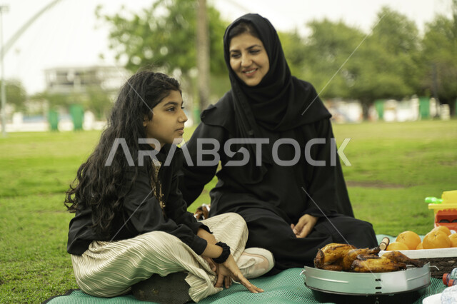 انشطة ترفيهيه صيفية، النقاشات والدردشة بين أفراد العائلة، التنزه في الهواء الطلق, أم عربية اماراتية خليجية في احدى الحدائق والمنتزهات مع ابنتها في الخارج, عائلة سعودية تقضي أوقات ممتعه مع الابناء, الاعتناء بالأطفال والاهتمام بهم, ايماءات تدل على السعادة