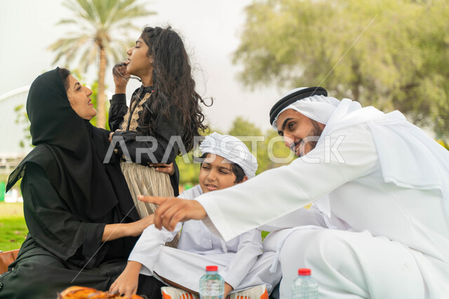 الدردشات و النقاشات بين أفراد العائلة، الاشارة الى شيء ما ،التنزه في الهواء الطلق في الحديقة, عائلة عربية اماراتية خليجية في احدى المنتزهات في الخارج, عائلة سعودية تقضي أوقات ممتعه مع الابناء, الاعتناء بالأطفال والاهتمام بهم, انشطة ترفيهيه صيفية
