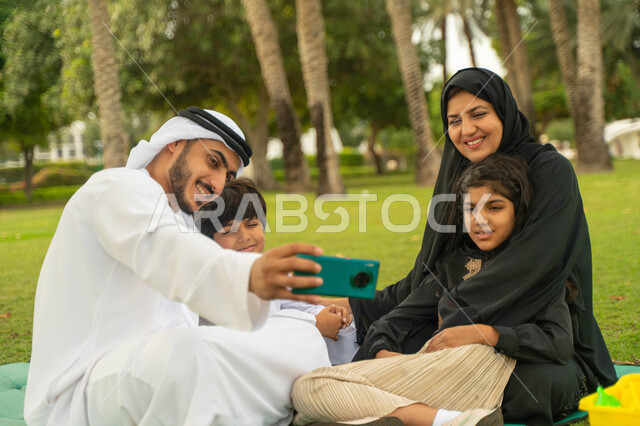 التقاط صور السيلفي للتجمعات العائلية الودية والذكريات عبر الجوال, عائلة عربية اماراتية خليجية في إحدى الحدائق والمنتزهات في الخارج, عائلة سعودية تقضي أوقات ممتعه مع الابناء, الاعتناء بالأطفال والاهتمام بهم, انشطة ترفيهيه صيفية, التنزه في الهواء الطلق