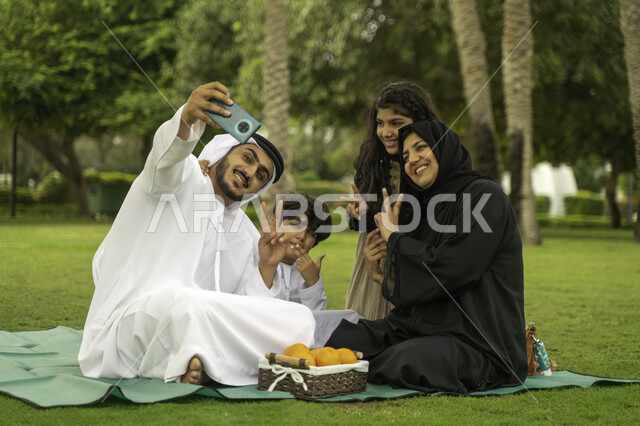 التنزه في الهواء الطلق, التقاط صور السيلفي للذكريات و التجمعات العائلية الودية عبر الجوال, عائلة عربية اماراتية خليجية في إحدى الحدائق والمنتزهات في الخارج, عائلة سعودية تقضي أوقات ممتعه مع الابناء, الاعتناء بالأطفال والاهتمام بهم, انشطة ترفيهيه صيفية