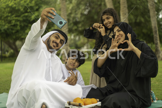 ايماءات يدين تدل على الحب, التقاط صور السيلفي التذكارية عبر الجوال, عائلة عربية اماراتية خليجية في إحدى الحدائق والمنتزهات في الخارج, التنزه في الهواء الطلق, عائلة سعودية تقضي أوقات ممتعه مع الابناء, الاعتناء بالأطفال والاهتمام بهم, انشطة ترفيهيه صيفيه
