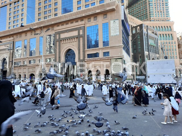 حجاج بيت الله الحرام في الفناء الخارجي للحرم المكي في مكة المكرمة بالمملكة العربية السعودية، الابراج والفنادق المطلة على الحرم المكي، حجاج بيت الله يطعمون الحمام، معالم اسلامية، السياحة الدينية في السعودية