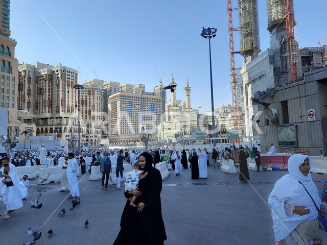 حجاج بيت الله الحرام في الفناء الخارجي للحرم المكي في مكة المكرمة بالمملكة العربية السعودية، الابراج والفنادق المطلة على الحرم المكي، حجاج بيت الله يطعمون الحمام، معالم اسلامية، السياحة الدينية في السعودية