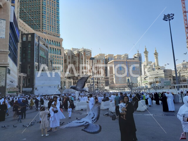 حجاج بيت الله الحرام في الفناء الخارجي للحرم المكي في مكة المكرمة بالمملكة العربية السعودية، الابراج والفنادق المطلة على الحرم المكي، حجاج بيت الله يطعمون الحمام، معالم اسلامية، السياحة الدينية في السعودية