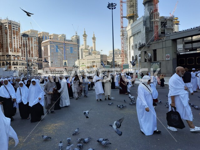 حجاج بيت الله الحرام في الفناء الخارجي للحرم المكي في مكة المكرمة بالمملكة العربية السعودية، الابراج والفنادق المطلة على الحرم المكي، حجاج بيت الله يطعمون الحمام، معالم اسلامية، السياحة الدينية في السعودية