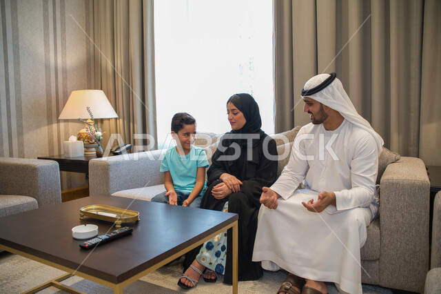 مفهوم تبادل الأحاديث والدردشات مع الأهل، مشاعر الألفه والمحبه بين أفراد العائله، أسره عربيه خليجيه اماراتيه تجلس في غرفه المعيشة، عائله سعوديه تقوم بالنقاش حول موضوع معين، ايماءات تدل على الجديه في الحوار، قضاء أوقات الفراغ في المنزل.