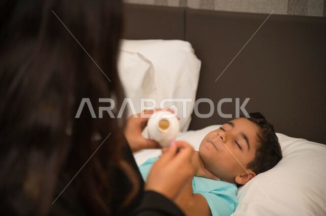 تناول الدواء بصورة آمنة والالتزام بالأوقات الصحيحة لشرب الدواء, معاناة الأطفال أثناء مرضهم واهتمام الأم بأولادها وتأثيره في حياة الأبناء, صورة مقربة لولد عربي خليجي إماراتي نائم يمر بحالة من المرض, أم سعودية تعطي ابنها المريض الشراب المناسب
