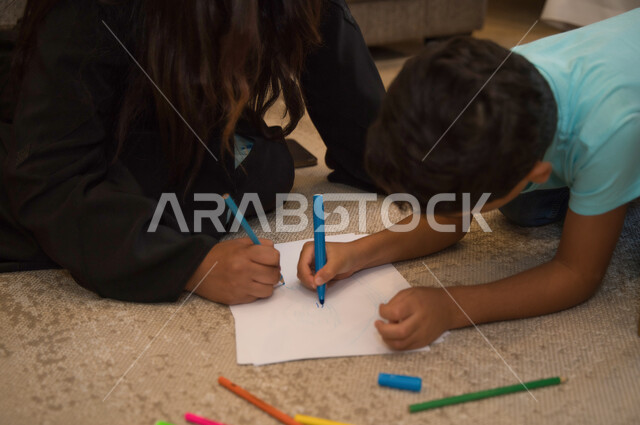 Care and interest in the upbringing and education of children, the participation of children in useful educational activities, the development of intellectual and mental skills in children, a close-up of an Arab Emirati mother drawing and coloring with her son, the concept of an interconnected Saudi family, spending enjoyable times at home.