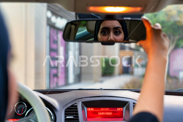 تعديل مرآة الرؤية الخلفية للسيارة، انعكاس صورة سائقة عربية إماراتية خليجية محجبة في مرآه السيارة، مفهوم الاستقلال و الحرية و الاعتماد على النفس، حرية القيادة للمرأة العربية، سيده سعودية ترتدي العباءة السوداء، اتباع قواعد السلامة العامة