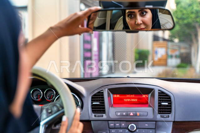 تعديل مرآة الرؤية الخلفية للسيارة، انعكاس صورة سائقة عربية إماراتية خليجية محجبة في مرآه السيارة، مفهوم الاستقلال و الحرية و الاعتماد على النفس، حرية القيادة للمرأة العربية، سيده سعودية ترتدي العباءة السوداء، اتباع قواعد السلامة