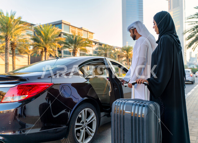 مفهوم السياحة والسفر عن طريق البر، رجل عربي خليجي إماراتي يرتدي الكندورة والغترة يفتح باب السيارة لإمرأة سعودية محجبة ترتدي العباءة السوداء تمسك بيدها حقيبة سفر، خدمة توصيل الركاب من وإلى المطار، خدمات النقل المريحة و الآمنة، رحلات سياحية ممتعة