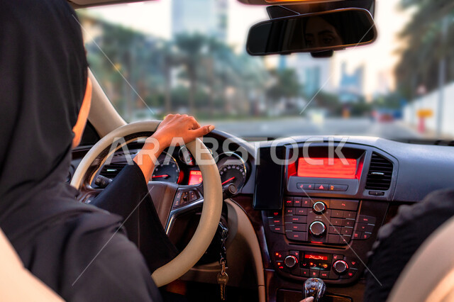 اتباع قواعد السلامة والقياده بحذر، مفهوم الاستقلال و الحرية و الاعتماد على النفس، انعكاس صورة شابة عربية إماراتية خليجية محجبة في مرآه السيارة،  سيده سعودية ترتدي العباءة السوداء تقوم بقيادة سيارتها، اعتماد المرأة على نفسها في التنقل والمواصلات