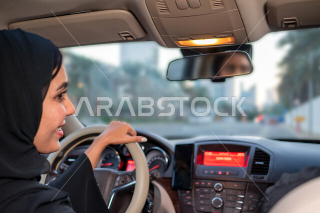 الحفاظ على الأمن والسلامة، مفهوم الاستقلال و الحرية و الاعتماد على النفس، انعكاس صورة شابة عربية إماراتية خليجية محجبة في مرآه السيارة،  سيده سعودية ترتدي العباءة السوداء تقوم بقيادة سيارتها، اعتماد المرأة على نفسها في التنقل والمواصلات