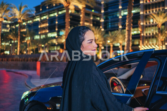 سيده سعودية ترتدي العباءة تقوم بفتح باب السيارة، الاستعداد لركوب السياره، مفهوم الاستقلال و الحرية و الاعتماد على النفس، امرأه عربية خليجية اماراتيه محجبة تقف بجانب سيارتها، حرية القيادة للمرأة العربية، اعتماد المرأه على نفسها في التنقل و المواصلات.