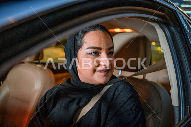 ايماءات التركيز في الإشارات المرورية، سيدة إماراتيه محجبة تجلس داخل سيارتها، إتقان قيادة المرأة للسيارة في الطرق الرئيسية، إمرأة عربية سعودية خليجية ترتدي حزام الأمان تقود بحذر، مفهوم الاستقلال والاعتماد الذاتي، الإلتزام بقواعد الأمن والسلامة العامة.