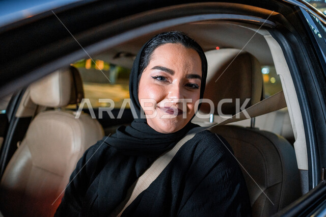 أهمية تعلم القيادة للسيدات، شابه إماراتيه محجبة مبتسمة تنظر الى الكاميرا، إتقان قيادة المرأة للسيارة في الطرق الرئيسية، إمرأة عربية سعودية خليجية تجلس داخل سيارتها ترتدي حزام الأمان، مفهوم الاستقلال والاعتماد الذاتي، الإلتزام بقواعد الأمن والسلامة العامة.
