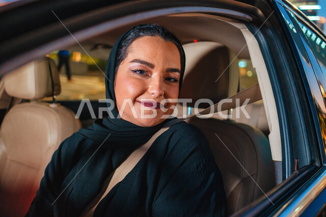 أهمية تعلم القيادة للسيدات، شابه إماراتيه محجبة مبتسمة تنظر الى الكاميرا، إتقان قيادة المرأة للسيارة في الطرق الرئيسية، إمرأة عربية سعودية خليجية تجلس داخل سيارتها ترتدي حزام الأمان، مفهوم الاستقلال والاعتماد الذاتي، الإلتزام بقواعد الأمن والسلامة العامة.