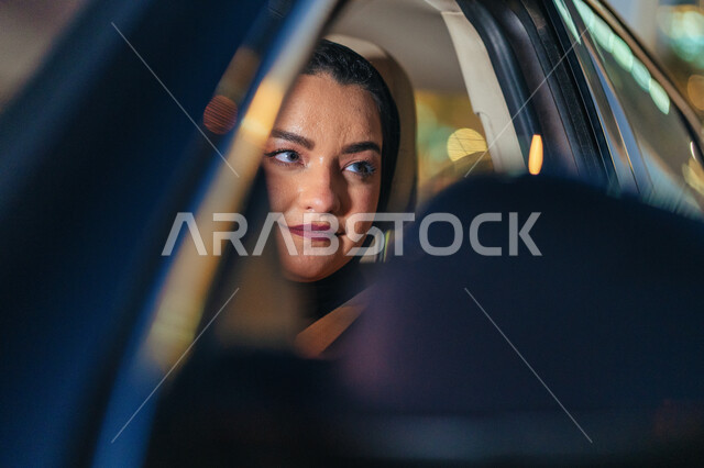 اتقان المرأة لقيادة السيارة في الطرق و الشوارع العامة، صورة مقربة لسيدة عربية اماراتيه خليجية تجلس داخل سيارتها، مفهوم الحرية و الاستقلال و الاعتماد على الذات، شابة سعودية محجبة تنظر لشيء ما، القيادة بحذر و اتباع قواعد الأمن و السلامة العامة.