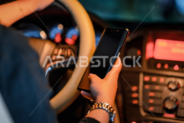 The concept of self-reliance and independence, driving in the streets and public roads, a close-up of a Saudi woman tracking the road via the Internet, an Arab Gulf Emirati woman sitting in her car holding a mobile phone, a woman's self-reliance in moveme