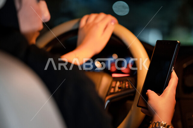 امرأه اماراتيه تجلس داخل سيارتها تحمل الهاتف المحمول، مفهوم الاعتماد على النفس والاستقلاليه، القيادة في الشوارع والطرق العامة، صورة مقربة لسيده  عربية خليجية سعودية تقوم بتتبع الطريق عبر الانترنت، اعتماد المرأه على نفسها في التنقل والمواصلات.