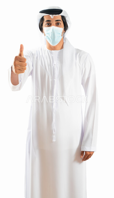 بورتريه من الجانب لرجل أعمال عربي خليجي اماراتي يرتدي الكمامة الواقية ويرفع اصبع الابهام لاعلى، إيماءات وتعابير يدين تدل على الاعجاب والرضى، القبول والموافقة، حركة اصبع واشارات، الالتزام باجراءات الوقاية من فايروس كورونا، خلفية بيضاء