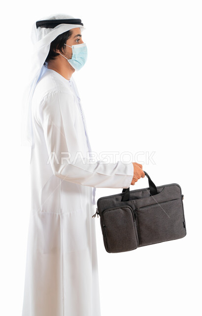 بورتريه من الجانب لرجل أعمال عربي خليجي اماراتي يرتدي الكمامة الواقية ويحمل حقيبة العمل، الوقوف باستقامة، الذهاب للعمل، الالتزام باجراءات الوقاية من فايروس كورونا، خلفية بيضاء