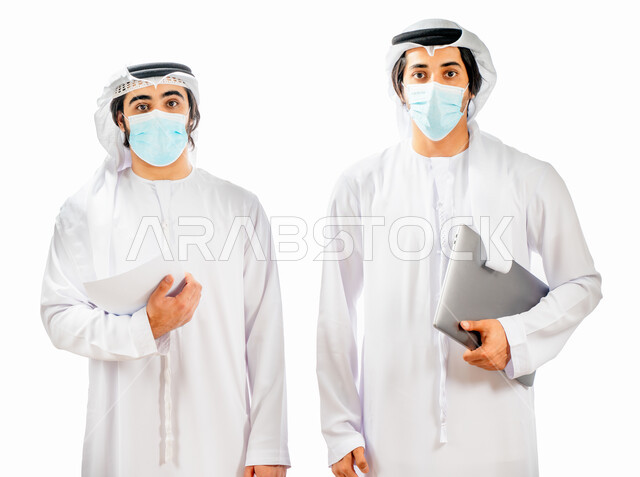 بورتريه لرجلان أعمال عربيان خليجيان اماراتيان يرتديان الكمامة الواقية، انجاز مهام العمل من خلال الحاسوب المحمول، متابعة العمل، بيئة العمل الاماراتي، الالتزام باجراءات الوقاية من فايروس كورونا، خلفية بيضاء