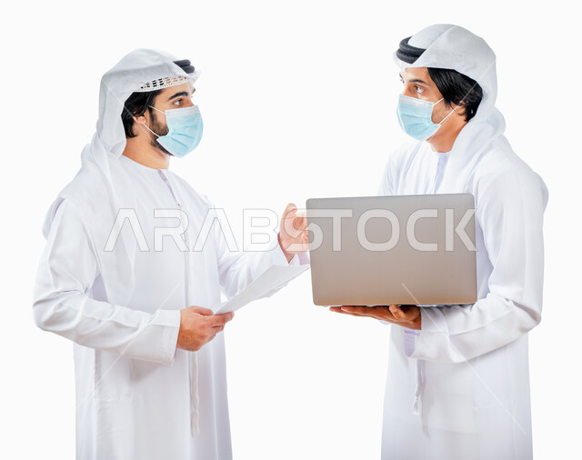 بورتريه لرجلان أعمال عربيان خليجيان اماراتيان يرتديان الكمامة الواقية، انجاز مهام العمل من خلال الحاسوب المحمول، نقاشات وحوارات عمل، متابعة العمل، بيئة العمل الاماراتي، الإشراف وتدقيق العمل، الالتزام باجراءات الوقاية من فايروس كورونا، خلفية بيضاء