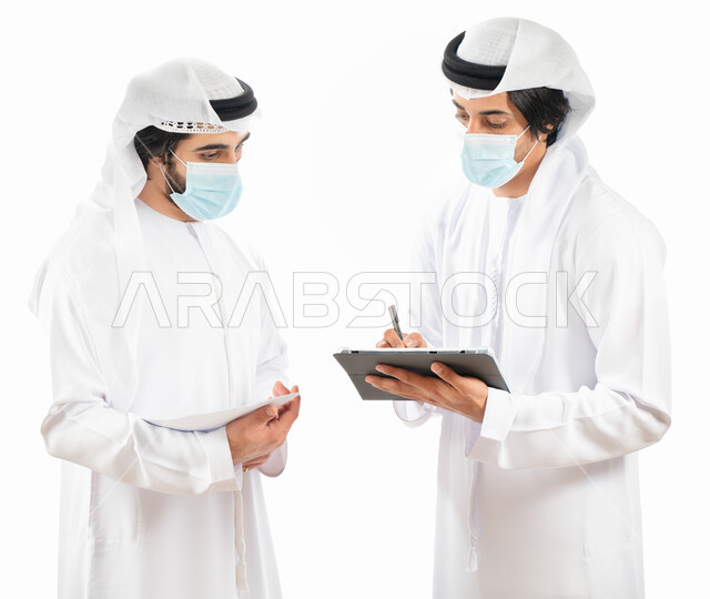 بورتريه لرجلان أعمال عربيان خليجيان اماراتيان يرتديان الكمامة الواقية، استخدام جهاز التابليت في شرح وتوضيح مهام العمل، نقاشات وحوارات عمل، متابعة العمل، بيئة العمل الاماراتي، الإشراف وتدقيق العمل، الالتزام باجراءات الوقاية من فايروس كورونا، خلفية بيضاء