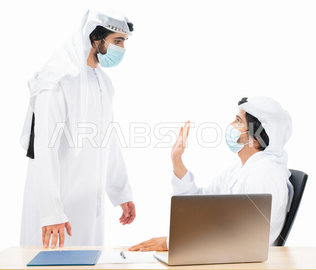 بورتريه لرجلان أعمال عربيان خليجيان اماراتيان يرتديان الكمامة الواقية، انجاز مهام العمل من خلال الحاسوب المحمول، نقاشات وحوارات عمل، متابعة العمل، بيئة العمل الاماراتي، الإشراف وتدقيق العمل، الالتزام باجراءات الوقاية من فايروس كورونا، خلفية بيضاء