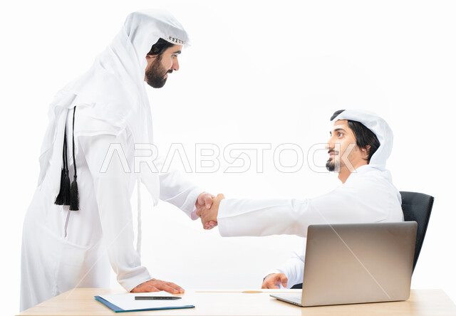 بورتريه لرجلان أعمال عربيان خليجيان اماراتيان يتصافحان، انجاز مهام العمل من خلال الحاسوب المحمول، نقاشات وحوارات عمل، زملاء عمل، بيئة العمل الاماراتي، الاشراف وتدقيق العمل، خلفية بيضاء