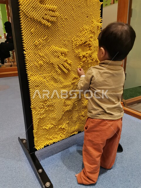 صورة من الخلف لطفل صغير يلعب بالألعاب الترفيهية ، ألعاب تعليمية ترفيهية ، تنمية قدرات و مهارات الطفل ، روضة أطفال ، حضانة أطفال ، أنشطة فنية وترفيهية  ، مراكز التنمية الفكرية