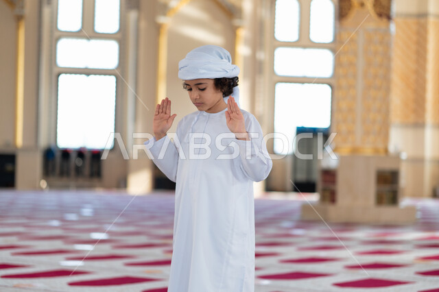 ولد صغير عربي خليجي إماراتي في أحد المساجد العربية، أداء فريضة الصلاة، يرفع يديه لتكبيرة الإحرام و البدء بالصلاة، العبادة والتقرب الى الله، أماكن إسلامية مقدسة، مفهوم أركان الإسلام، إسلاميات وعبادة