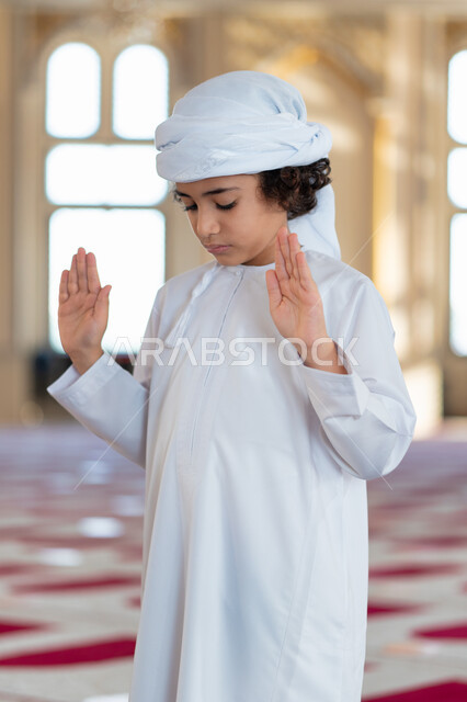 ولد صغير عربي خليجي إماراتي في أحد المساجد العربية، أداء فريضة الصلاة، يرفع يديه لتكبيرة الإحرام و البدء بالصلاة، العبادة والتقرب الى الله، أماكن إسلامية مقدسة، مفهوم أركان الإسلام، إسلاميات وعبادة